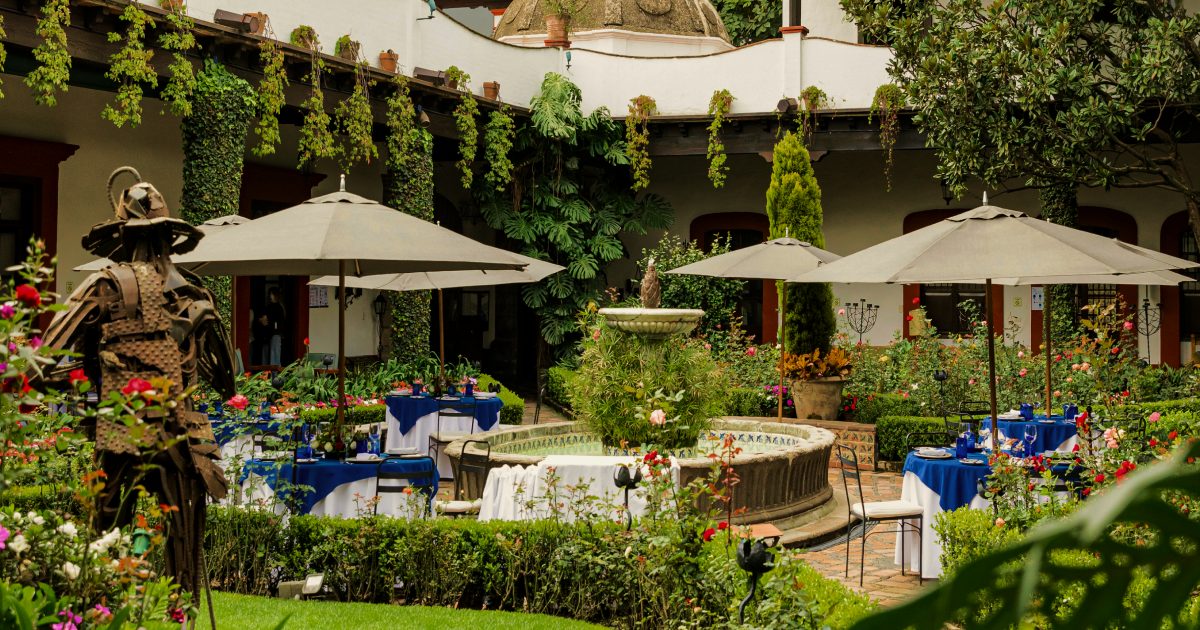 Courtyard of the original San Angel Inn in Mexico City, with umbrellas, fountain, and colonial arcade